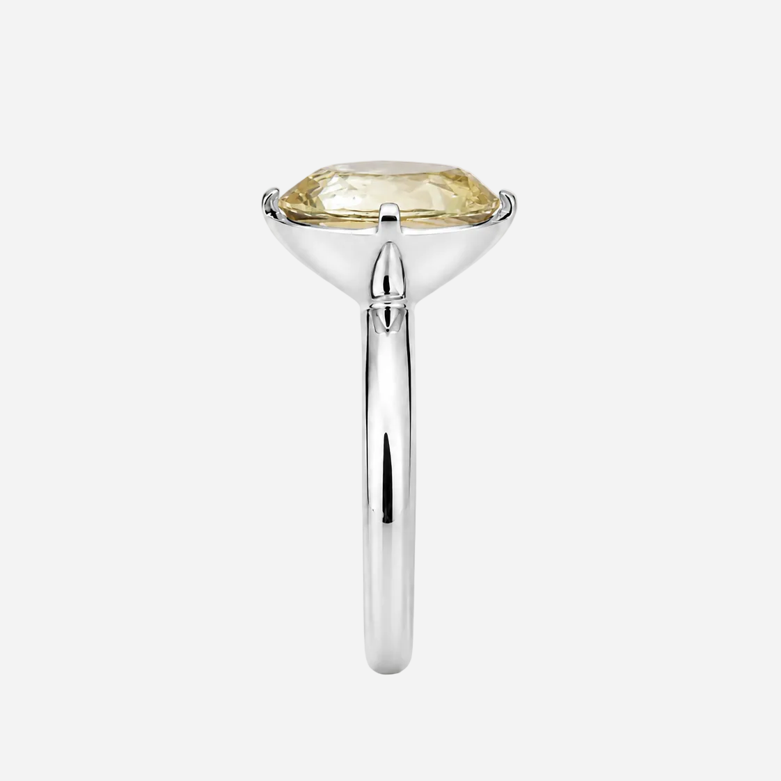 A silver-toned ring featuring a large, cushion-cut pale yellow gemstone in a prong setting, shown against a plain white background.