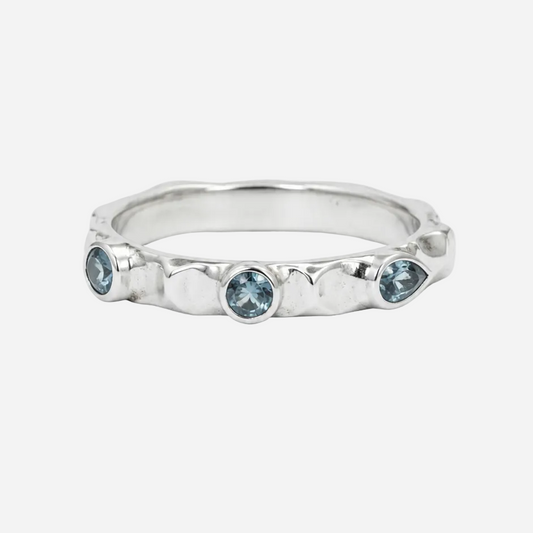 Silver ring with three blue gemstones on a white background