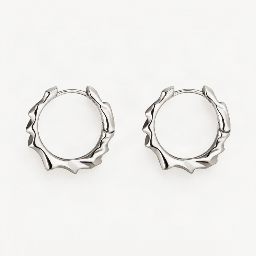 A pair of white gold-toned textured hoop earrings with a wavy, scalloped outer edge, displayed on a clean white background.