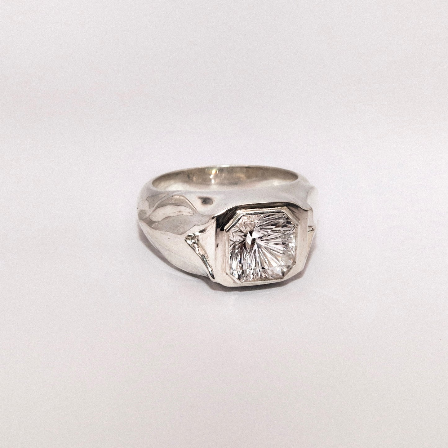 Silver ring with a large diamond on a white background