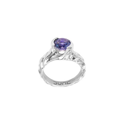 A sterling silver ring with a rhodium finish, featuring a natural bluish purple Tanzanite centerpiece with a Portuguese cut.