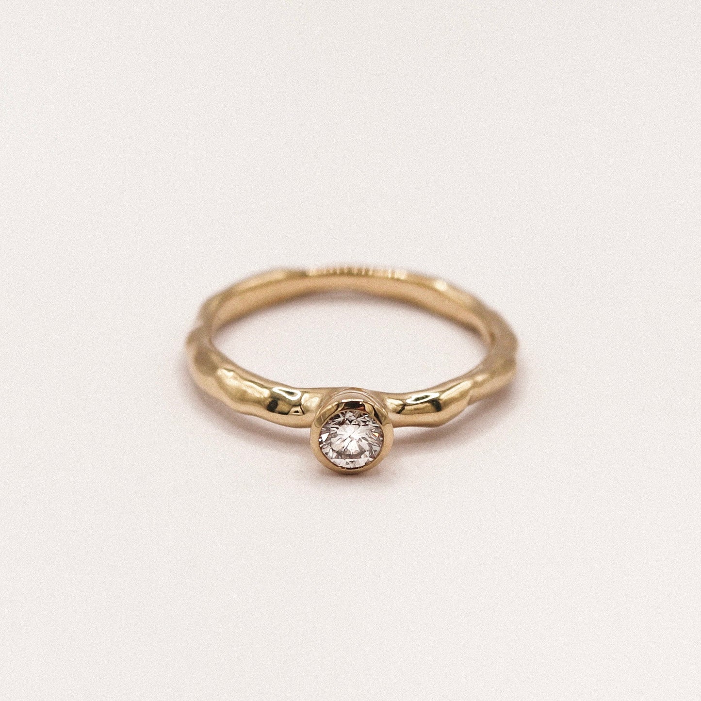 Gold ring with a diamond on a light beige background