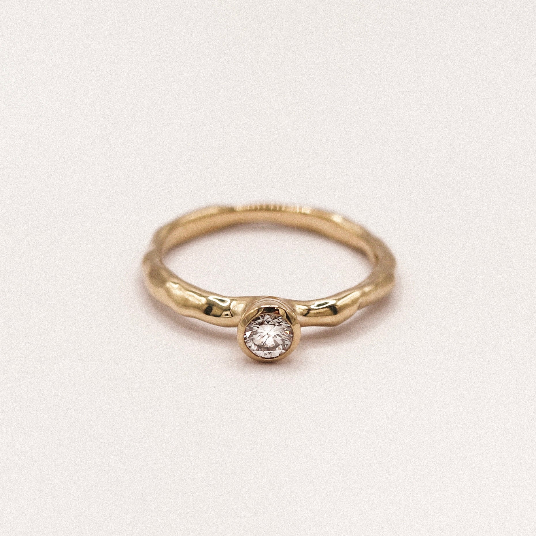 Gold ring with a diamond on a light beige background