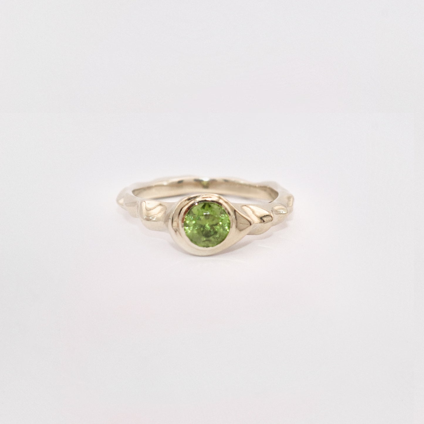 Gold ring with a green gemstone on a light gray background