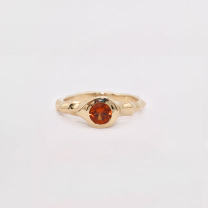 Gold ring with a red gemstone on a light gray background