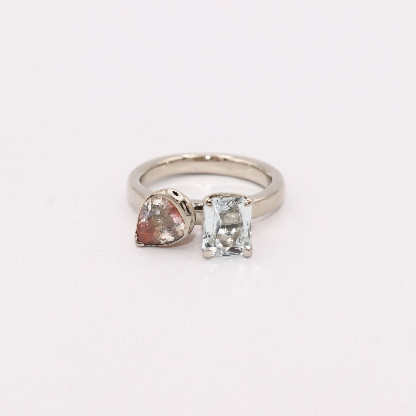 Silver ring with heart-shaped and rectangular gemstones on a white background