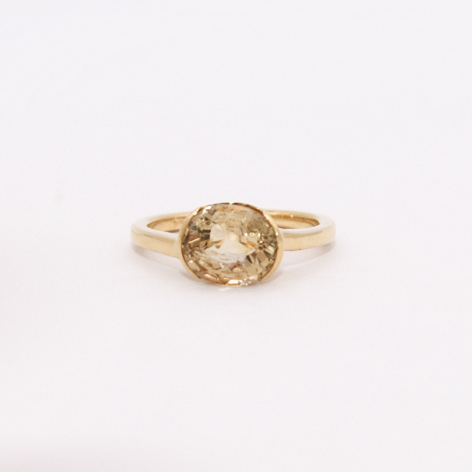 Gold ring with a yellow gemstone on a white background