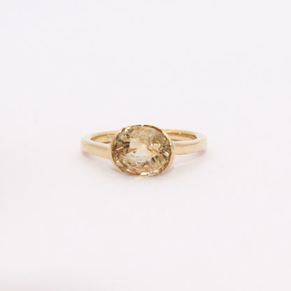 Gold ring with a yellow gemstone on a white background