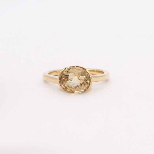 Gold ring with a yellow gemstone on a white background