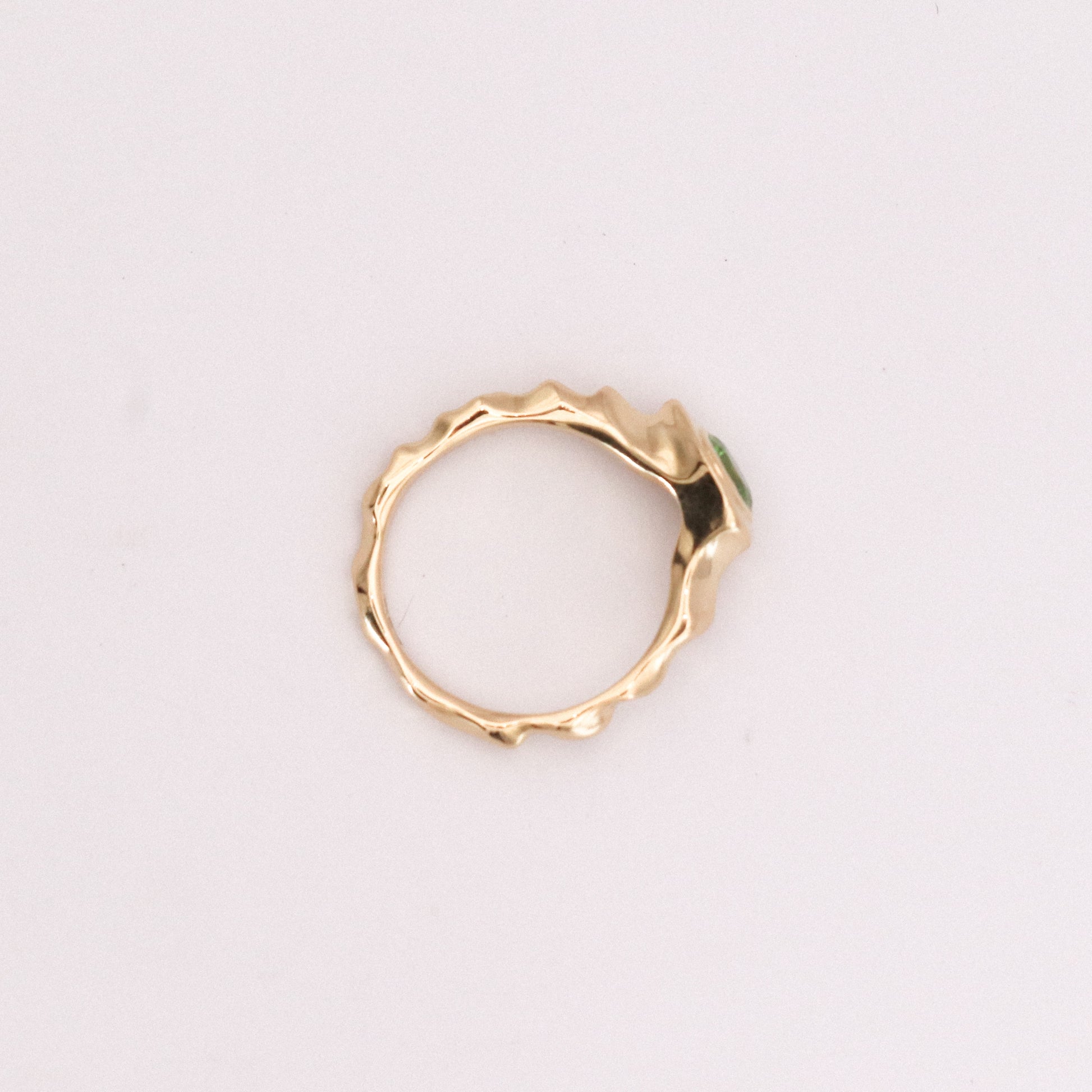 Gold ring with a textured design on a light gray background