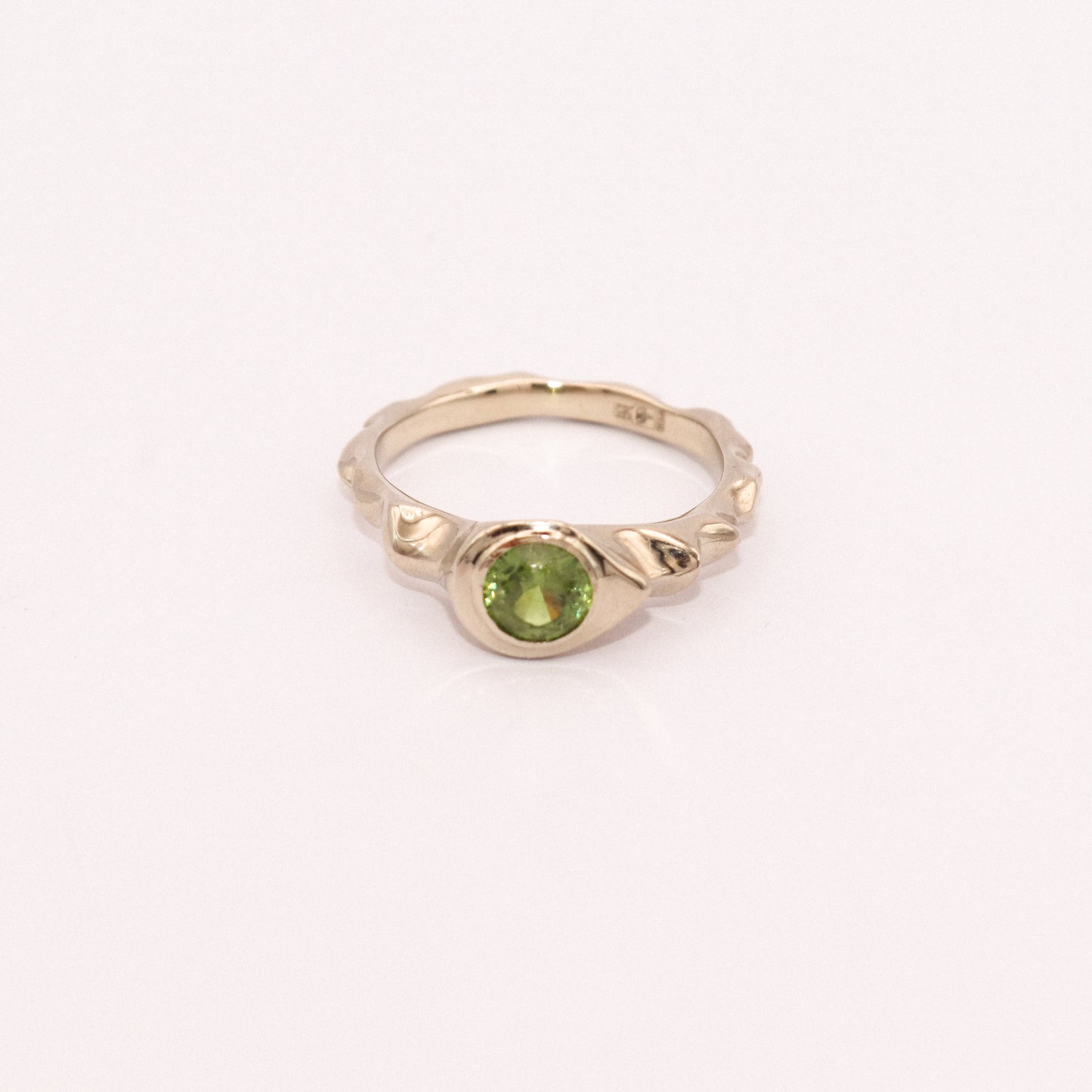 Gold ring with a green gemstone on a white background