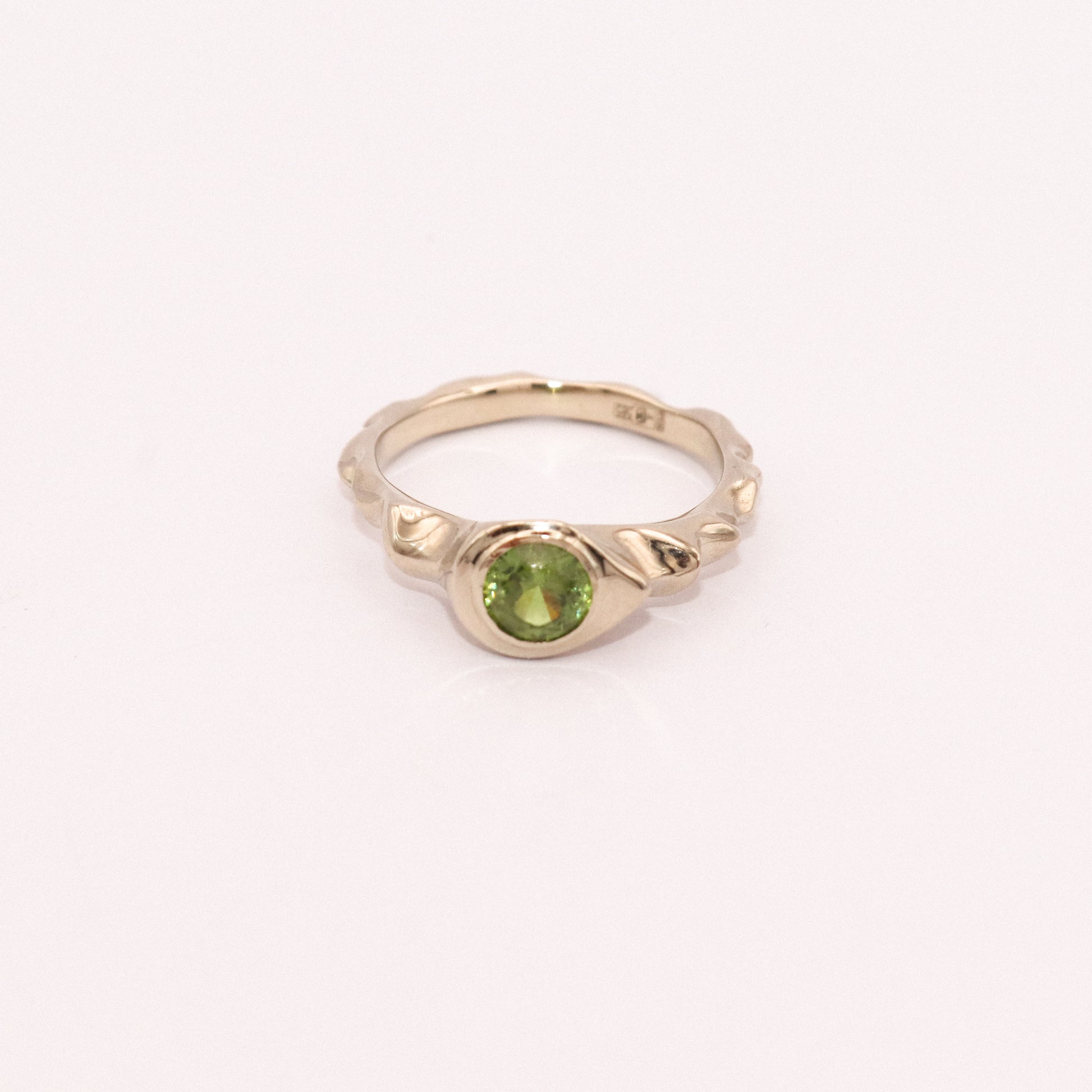 Gold ring with a green gemstone on a white background