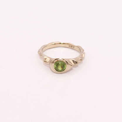 Gold ring with a green gemstone on a white background