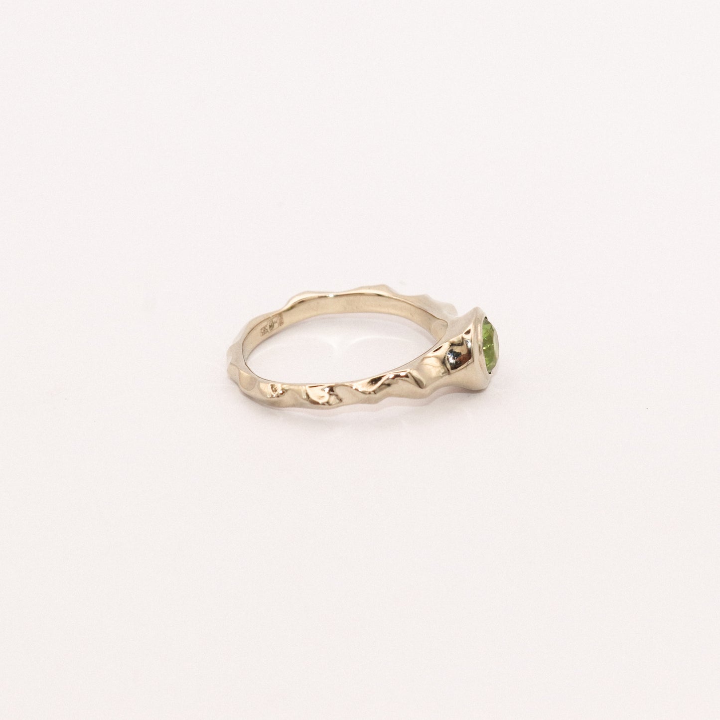 Gold ring with a green gemstone on a white background