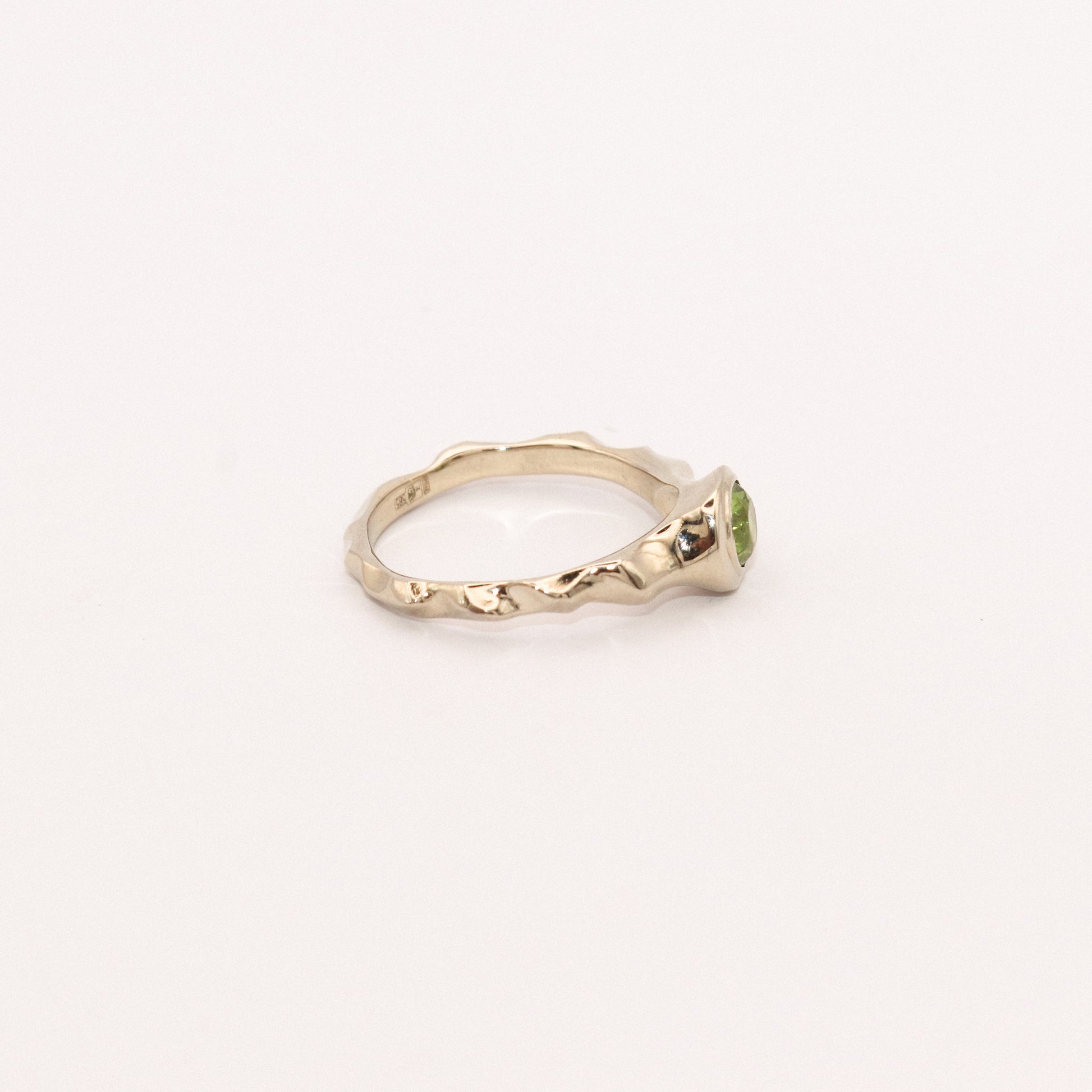 Gold ring with a green gemstone on a white background