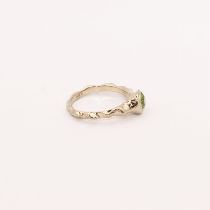 Gold ring with a green gemstone on a white background