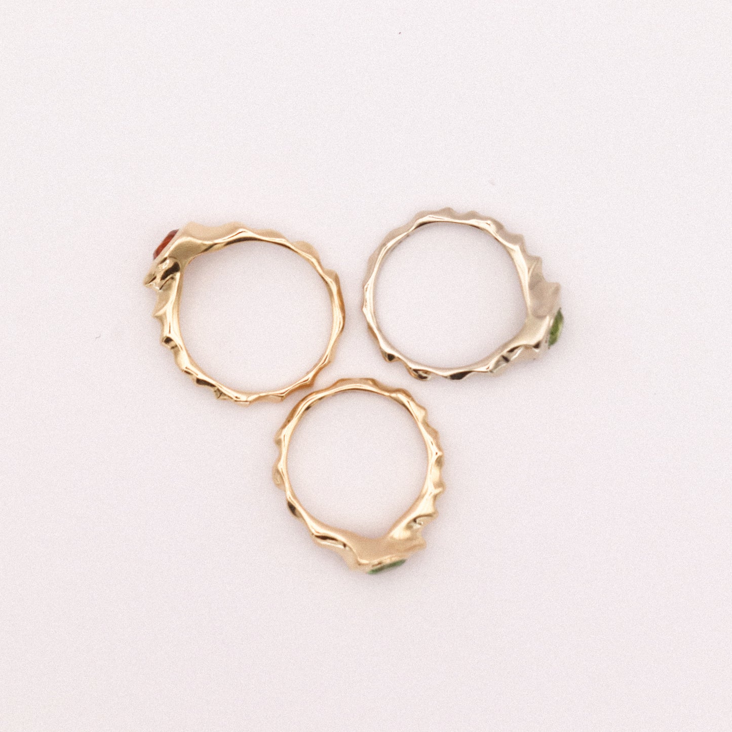 Three gold hoop earrings on a light pink background