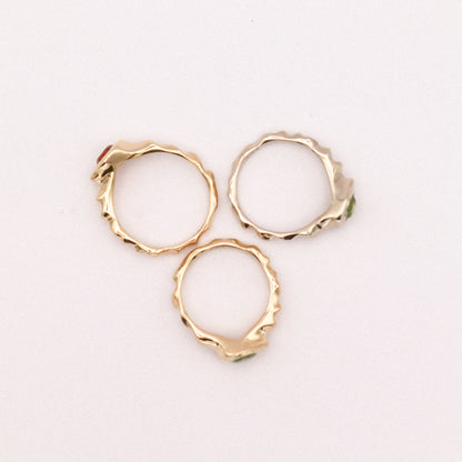Three gold hoop earrings on a light pink background
