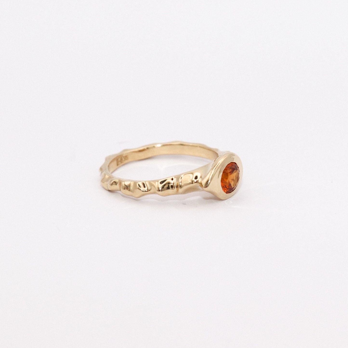 Gold ring with a gemstone on a light gray background
