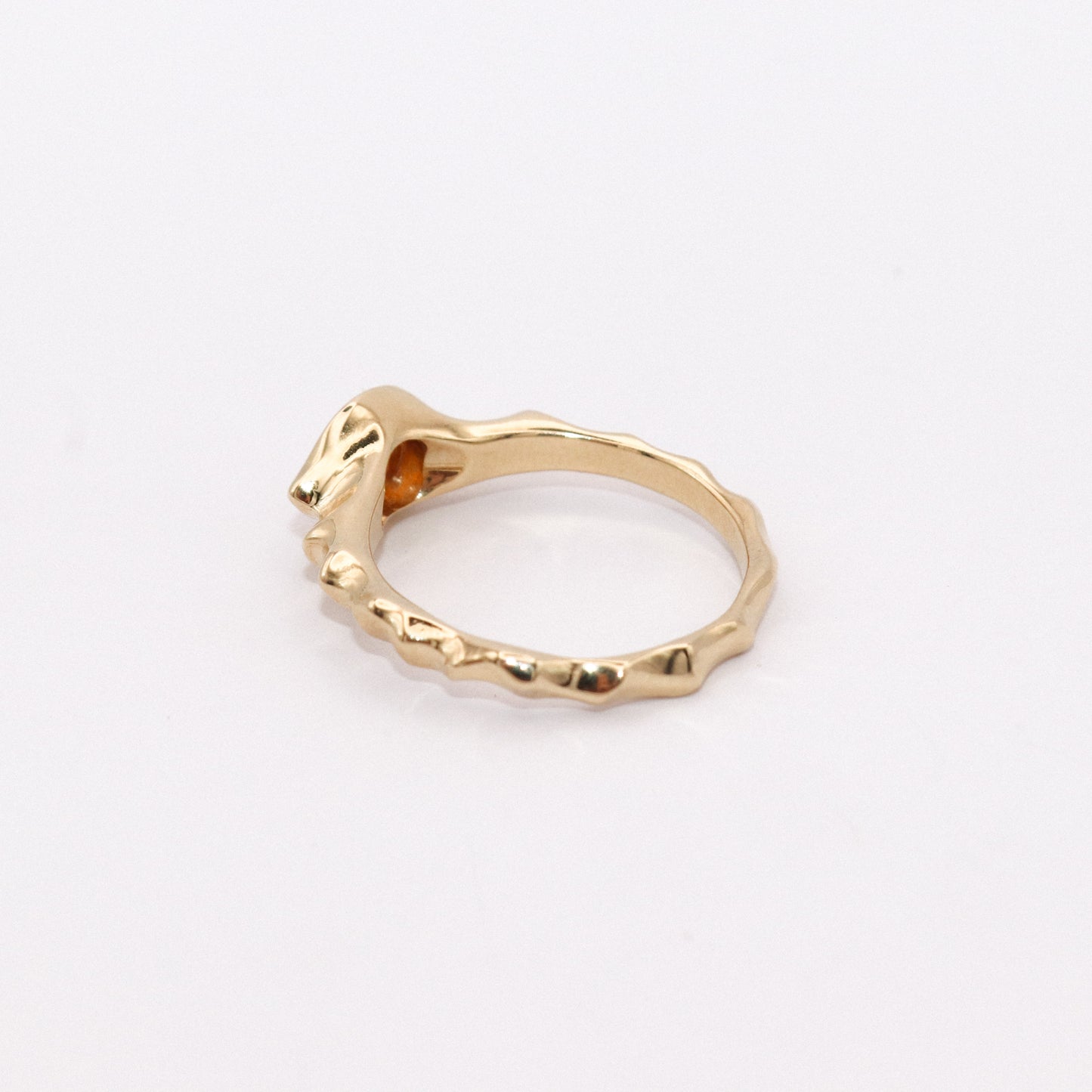 Gold ring with a unique design on a light gray background
