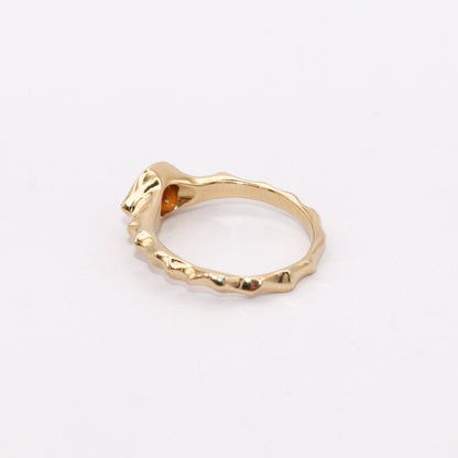 Gold ring with a unique design on a light gray background