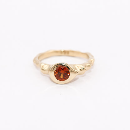 Gold ring with a red gemstone on a white background