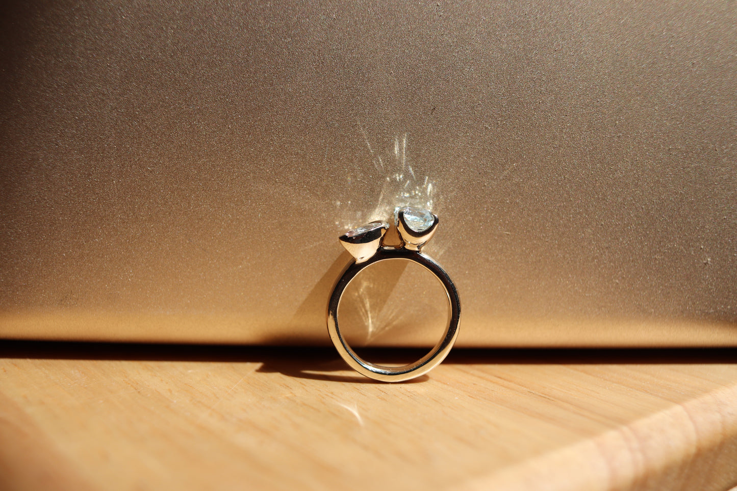 Gold ring with a heart-shaped gemstone on a wooden surface with a brown background