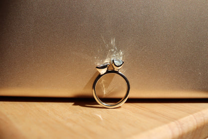 Gold ring with a heart-shaped gemstone on a wooden surface with a brown background