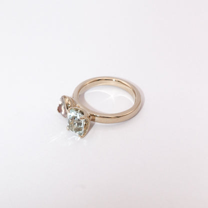 Gold ring with a heart-shaped green gemstone on a white background