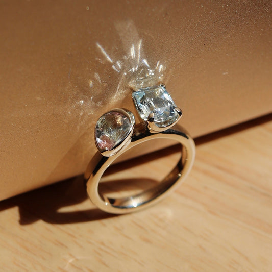 Gold ring with two gemstones on a wooden surface