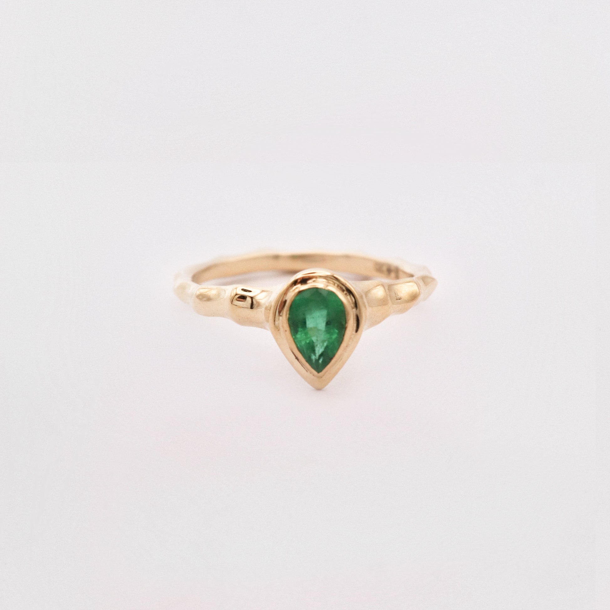 Gold ring with a green gemstone on a white background