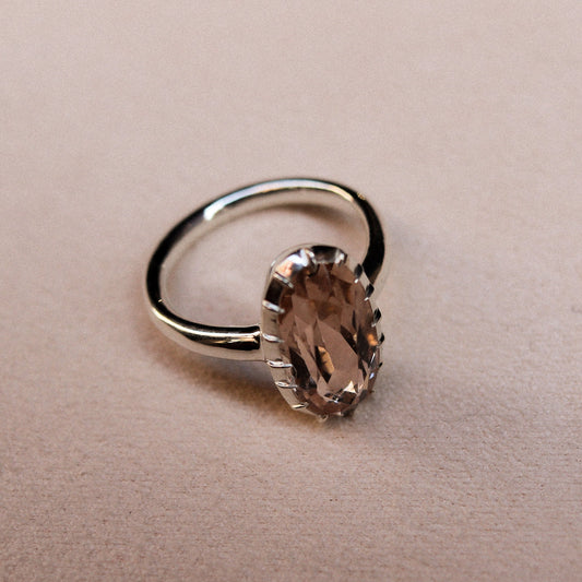 Silver ring with a brown gemstone on a beige background