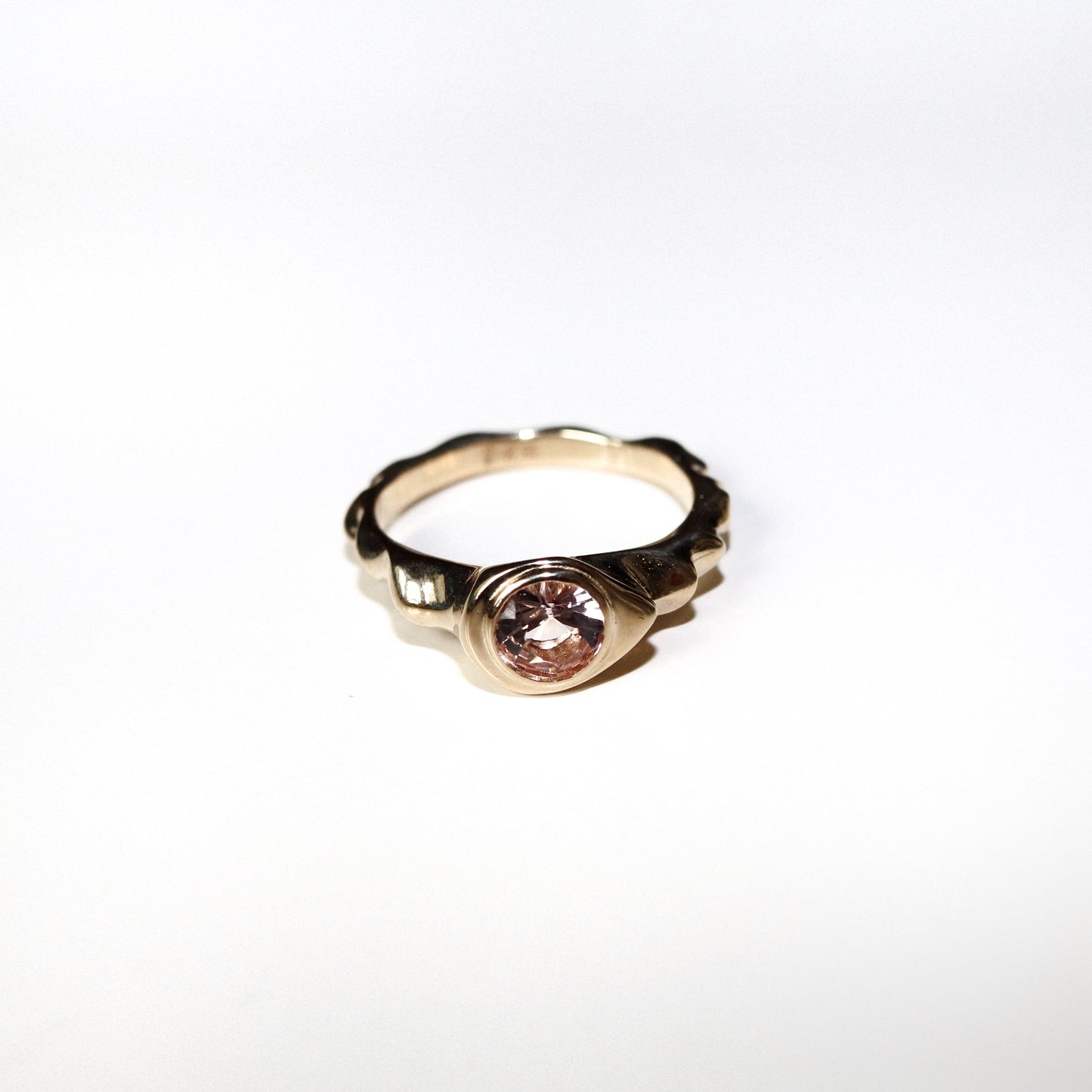 Gold ring with a pink gemstone on a white background