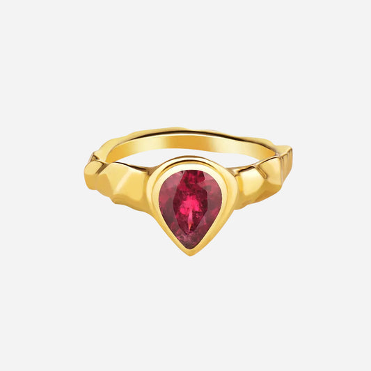 A pear cut rubellite stone set in a 14k gold ring, viewed from the front on a plain background.