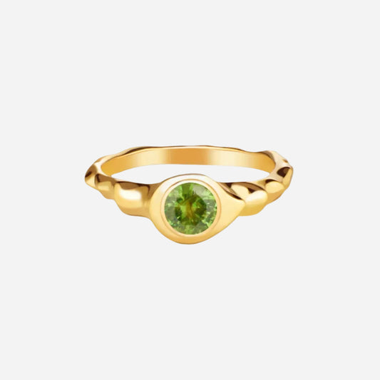 A 14k yellow gold ring with a round cut demantoid gemstone set in the center, against a white background.