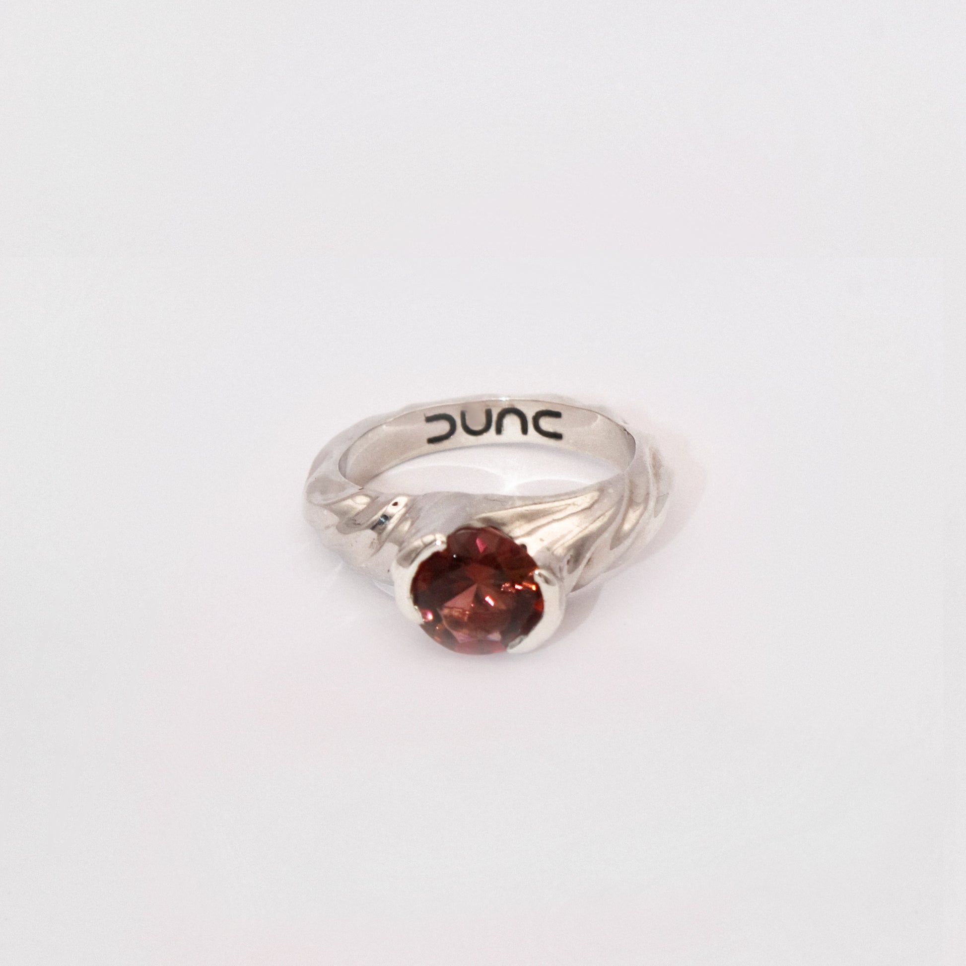 Silver ring with a red gemstone on a white background