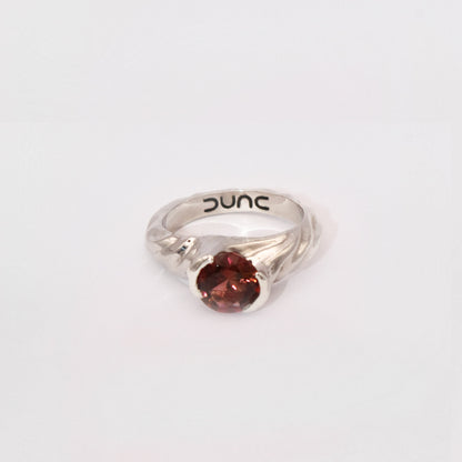 Silver ring with a red gemstone on a white background