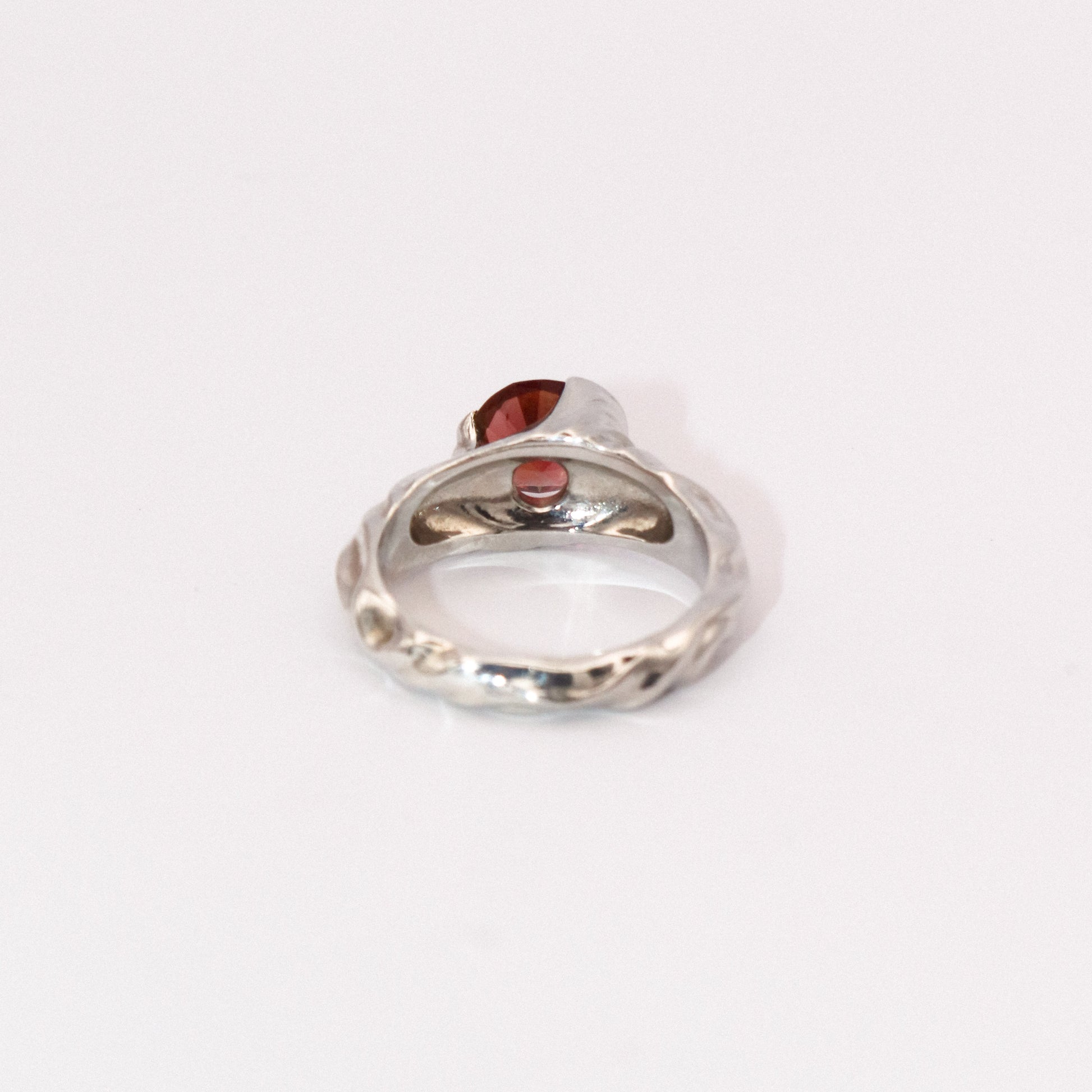 Silver ring with a red gemstone on a white background