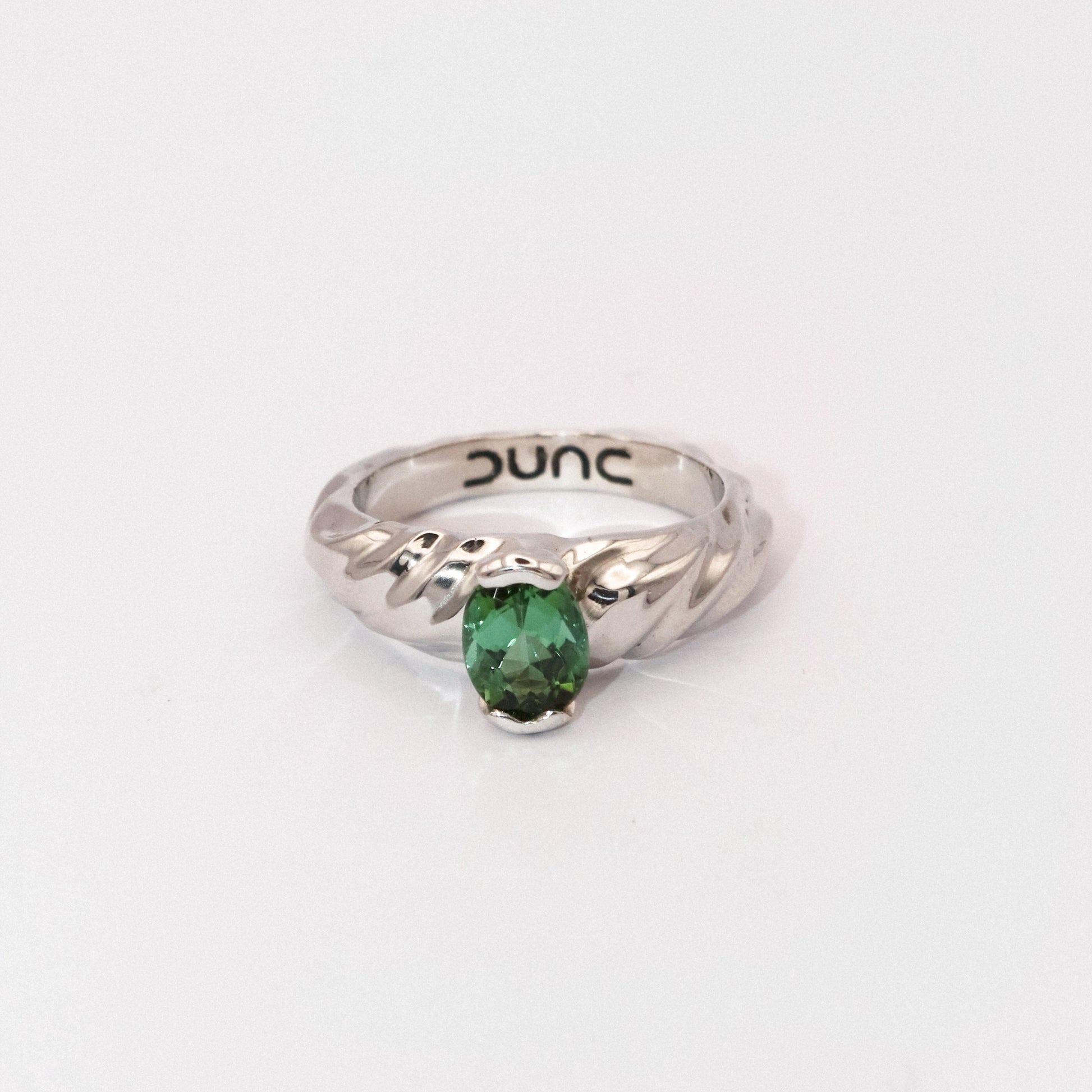 Silver ring with a green gemstone on a white background
