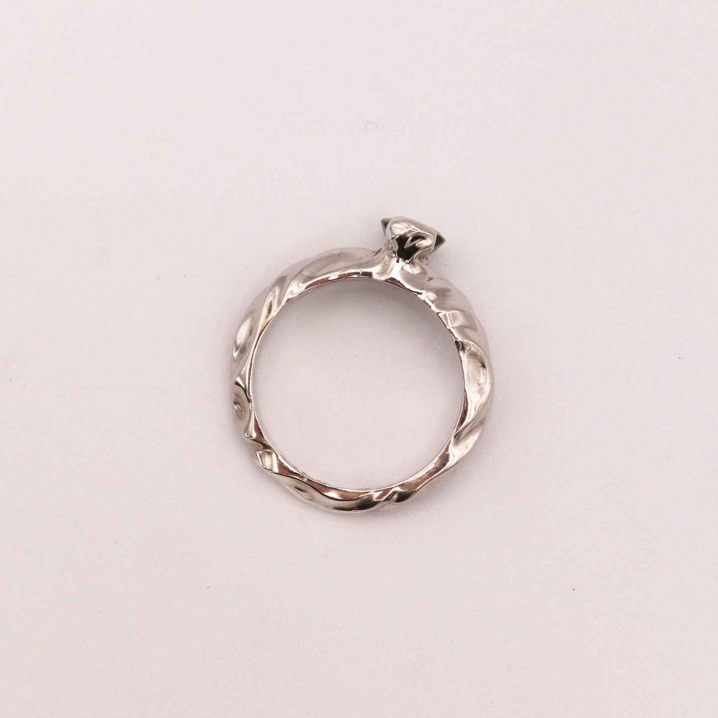 Silver ring with a diamond on a light pink background
