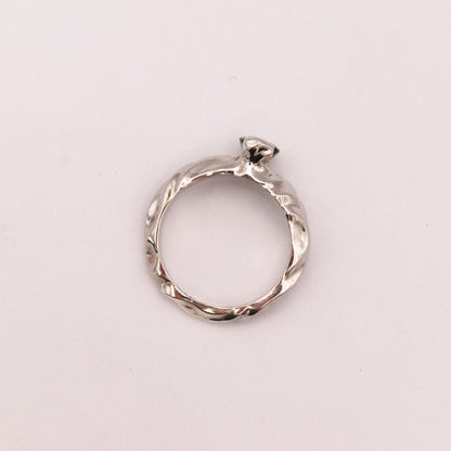 Silver ring with a diamond on a light pink background