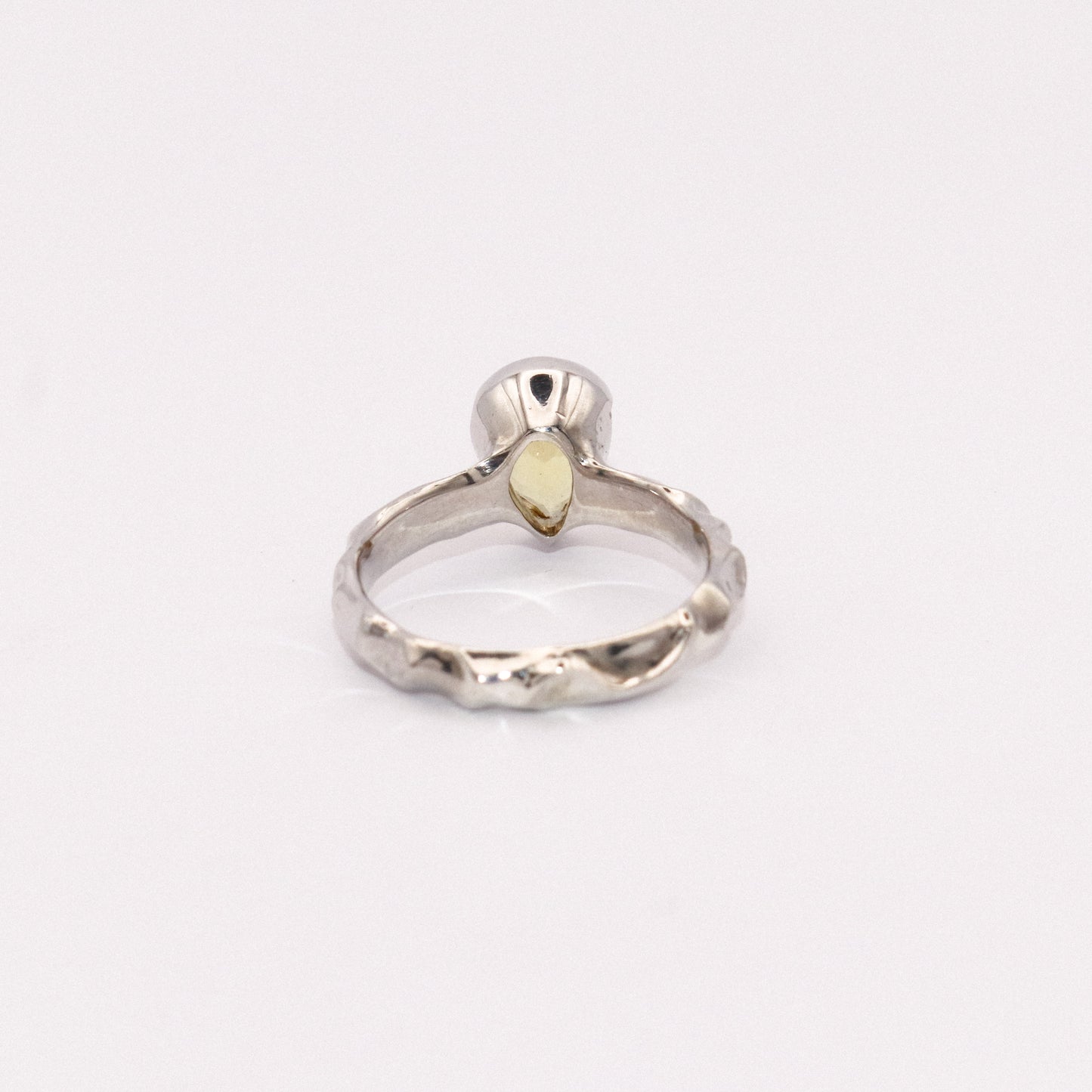 Silver ring with a yellow gemstone on a white background