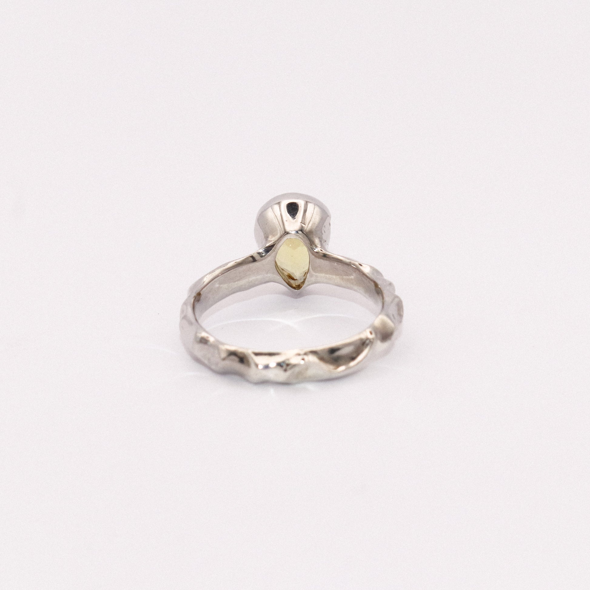 Silver ring with a yellow gemstone on a white background