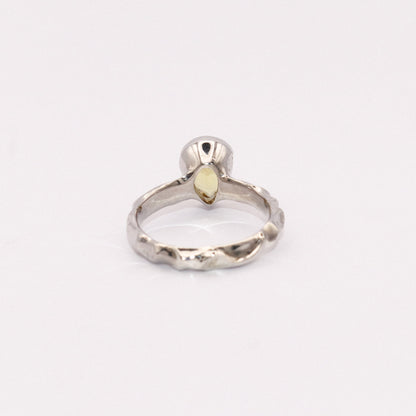 Silver ring with a yellow gemstone on a white background