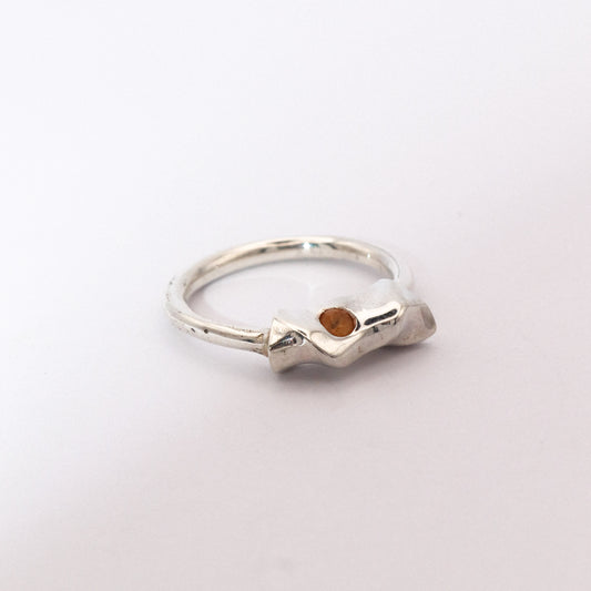 Silver ring with a small gemstone on a light gray background