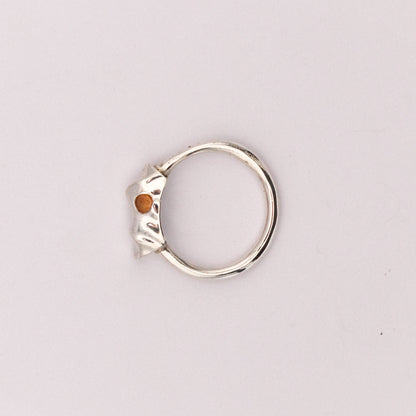 Silver ring with a small orange stone on a light gray background