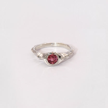 Silver ring with a pink gemstone on a light gray background