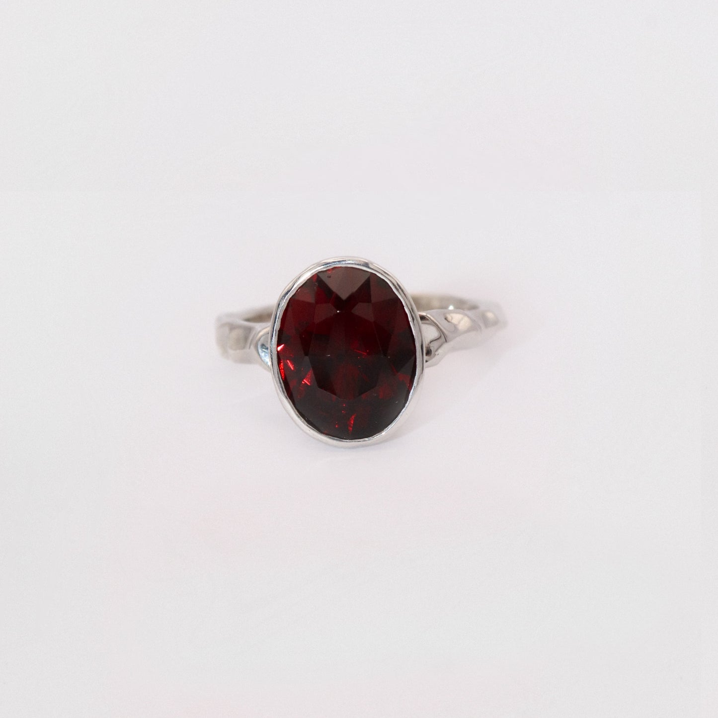 Silver ring with a red gemstone on a white background
