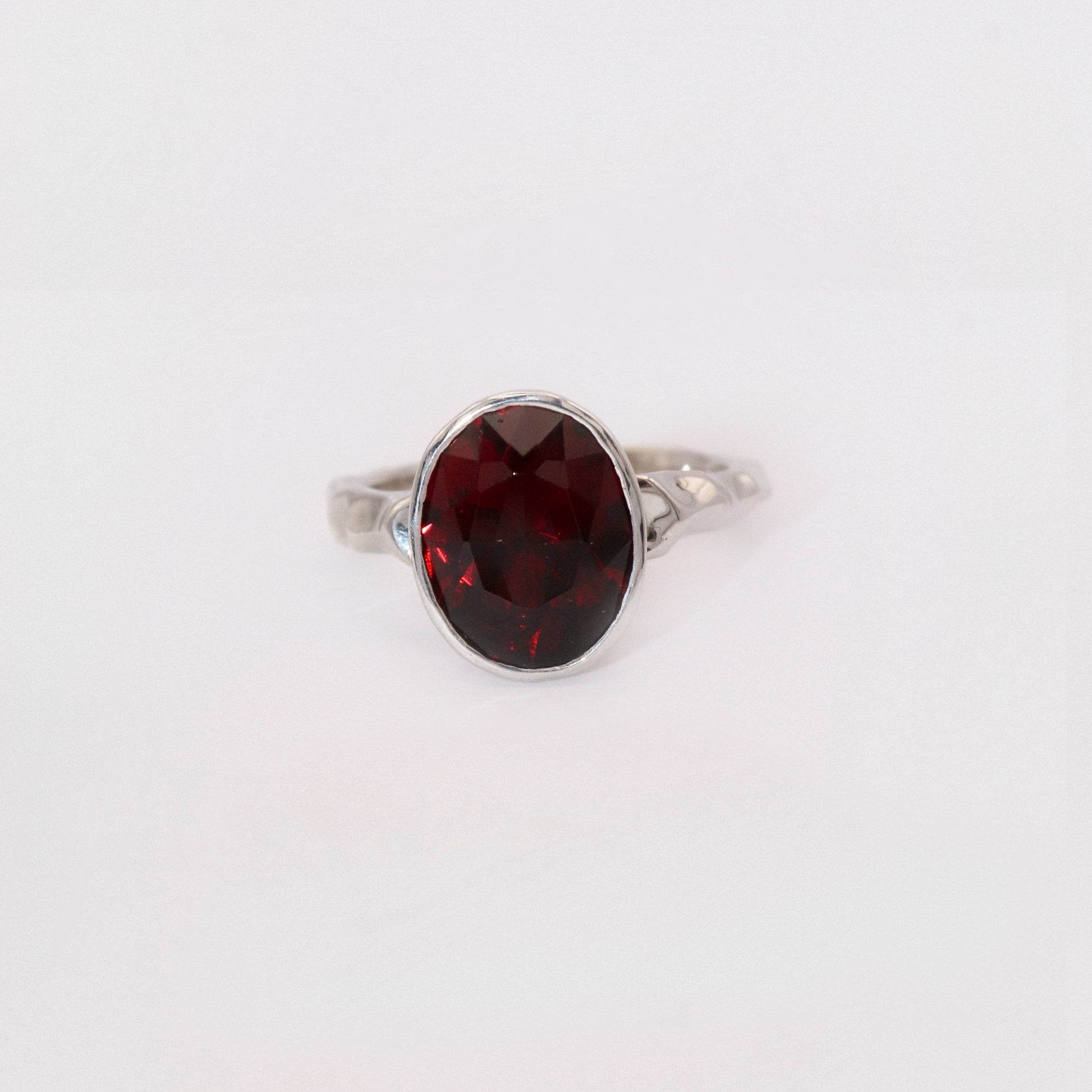 Silver ring with a red gemstone on a white background