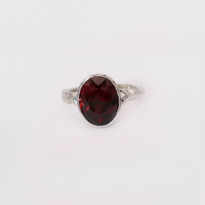 Silver ring with a red gemstone on a white background